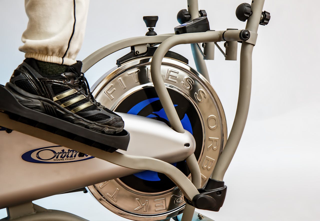 Foot on pedal of elliptical trainer showcasing fitness equipment and footwear close-up.